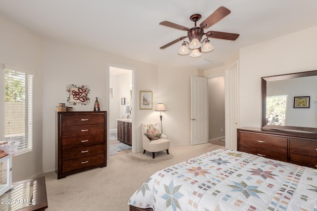 carpeted bedroom with ensuite bath, multiple windows, and ceiling fan