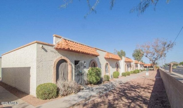 view of side of property featuring a tile roof and stucco siding