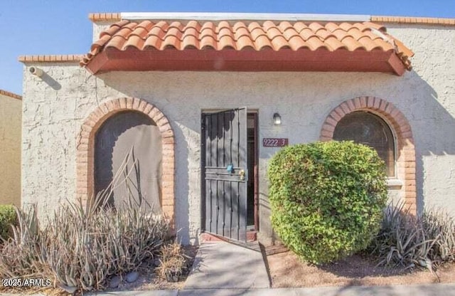 view of exterior entry featuring a tiled roof and stucco siding