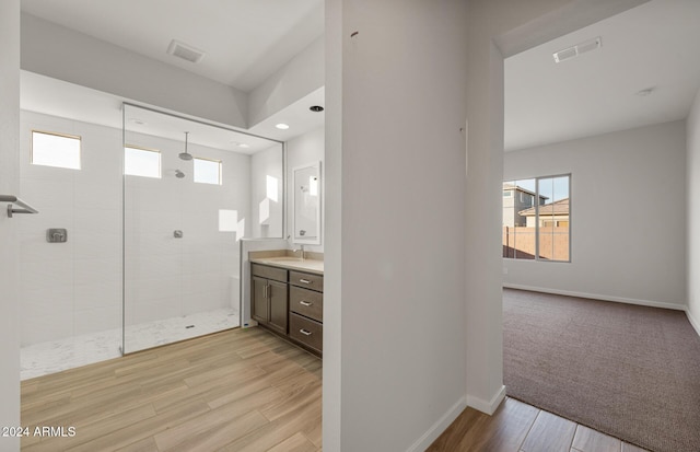 bathroom with vanity, a tile shower, and wood-type flooring