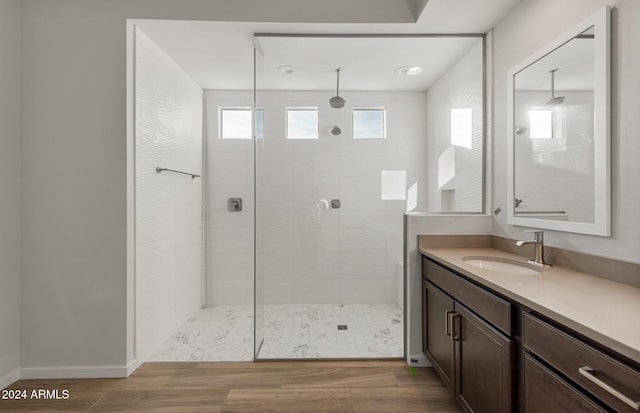 bathroom with hardwood / wood-style flooring, vanity, and a tile shower