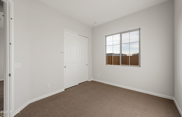 unfurnished bedroom with a closet and dark carpet