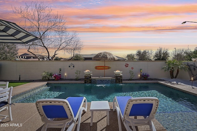 pool at dusk featuring a fenced in pool and a fenced backyard