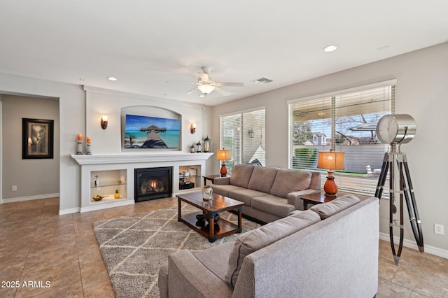 living room featuring visible vents, baseboards, recessed lighting, ceiling fan, and a glass covered fireplace