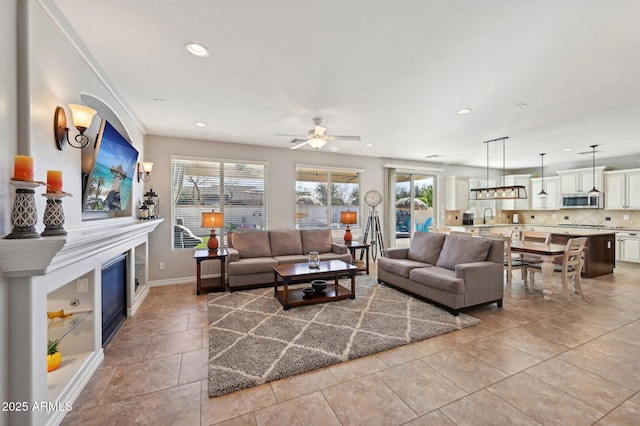 living area featuring light tile patterned floors, baseboards, recessed lighting, ceiling fan, and a glass covered fireplace