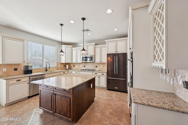 kitchen featuring visible vents, backsplash, light stone countertops, appliances with stainless steel finishes, and a sink