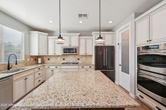 kitchen with visible vents, a sink, light stone counters, backsplash, and stainless steel appliances