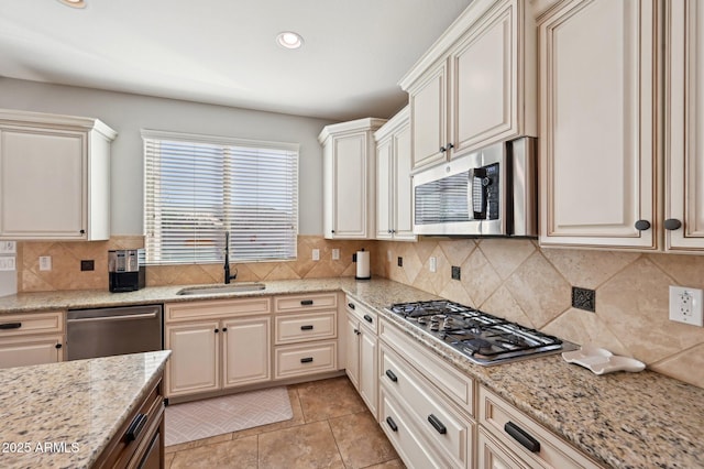 kitchen featuring a sink, light stone counters, tasteful backsplash, recessed lighting, and stainless steel appliances