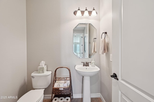 half bath featuring toilet and baseboards