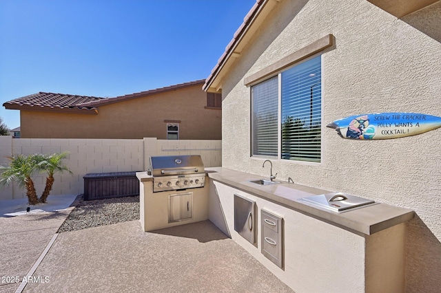 view of patio featuring a sink, grilling area, an outdoor kitchen, and fence