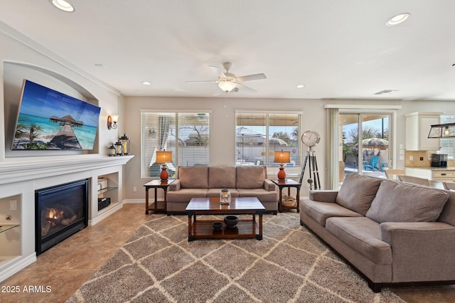 tiled living room with visible vents, a glass covered fireplace, recessed lighting, baseboards, and ceiling fan