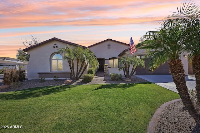 mediterranean / spanish-style home with stucco siding, driveway, an attached garage, and a front lawn