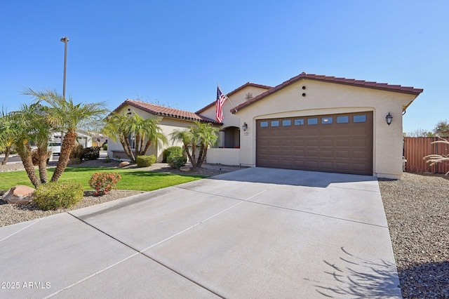 mediterranean / spanish house featuring stucco siding, concrete driveway, a front yard, an attached garage, and a tiled roof