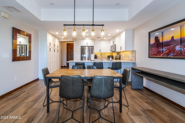 dining area featuring a tray ceiling and dark wood-type flooring