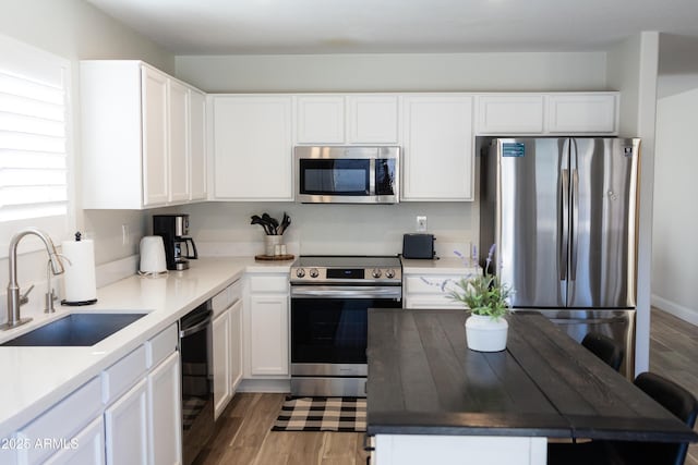 kitchen with wood-type flooring, white cabinetry, sink, and appliances with stainless steel finishes