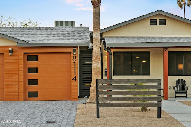 view of front of house featuring a garage, roof with shingles, and stucco siding