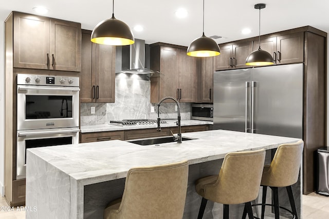 kitchen featuring a sink, backsplash, appliances with stainless steel finishes, wall chimney range hood, and dark brown cabinets