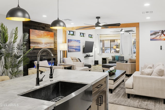 kitchen with visible vents, ceiling fan, open floor plan, hanging light fixtures, and a sink