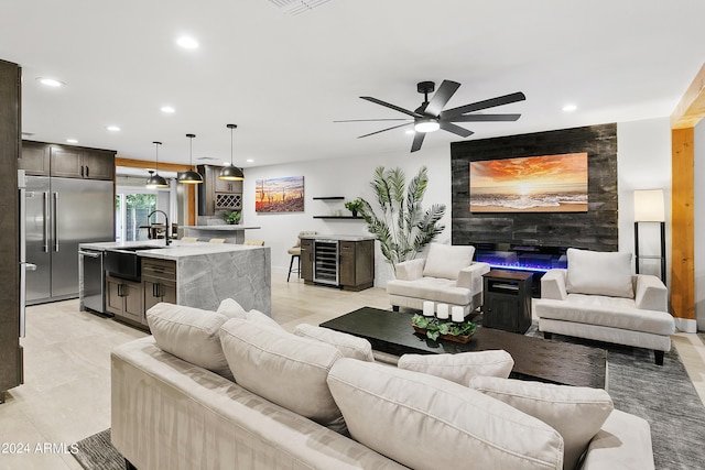 living room with a tiled fireplace, a ceiling fan, recessed lighting, wine cooler, and an accent wall