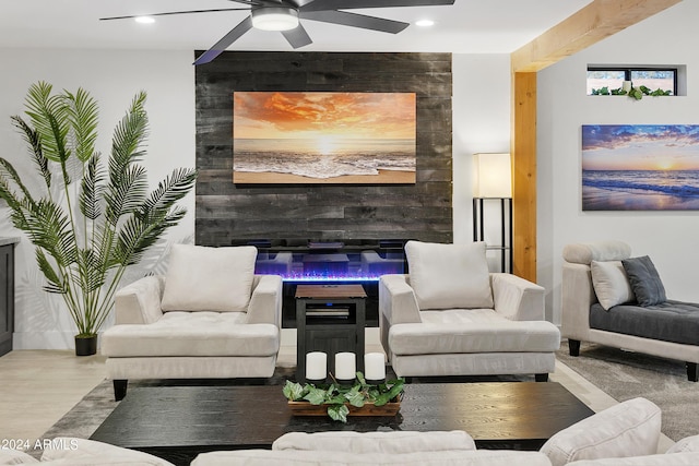 living area with a glass covered fireplace, wood finished floors, ceiling fan, and recessed lighting