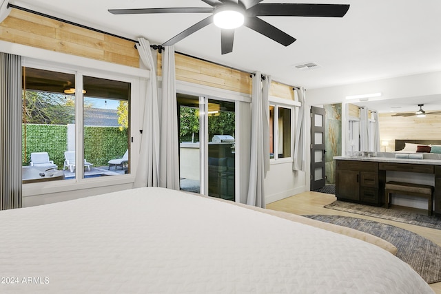 bedroom featuring visible vents, access to outside, a barn door, light wood-style floors, and wood walls