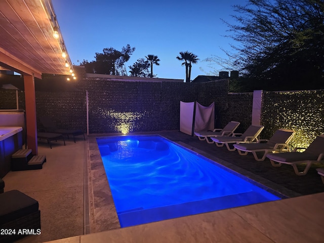 pool at dusk featuring a fenced in pool and a patio