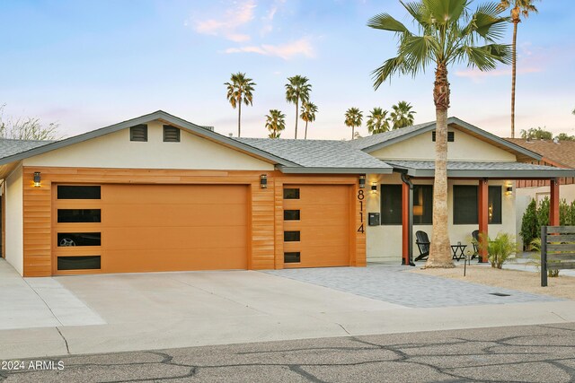 view of front of property featuring stucco siding, driveway, a garage, and roof with shingles