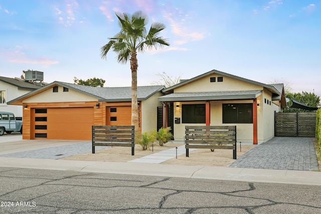 view of front of home with fence, stucco siding, cooling unit, a garage, and driveway