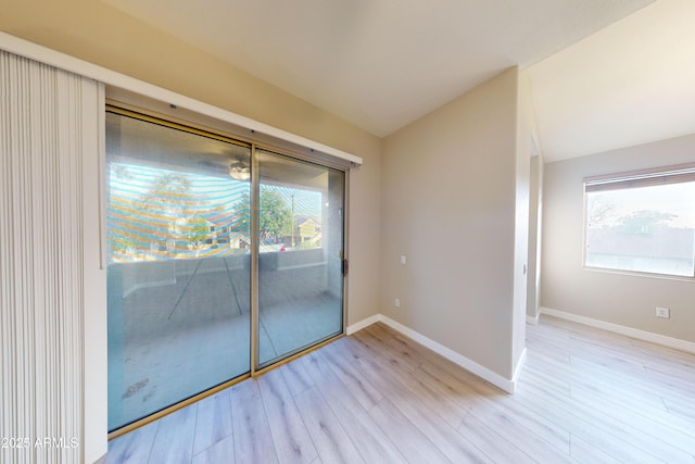 empty room with vaulted ceiling, a wealth of natural light, and light hardwood / wood-style floors