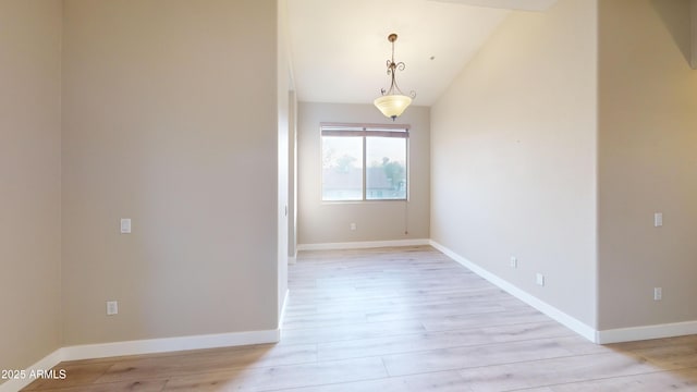 unfurnished room featuring lofted ceiling and light wood-type flooring