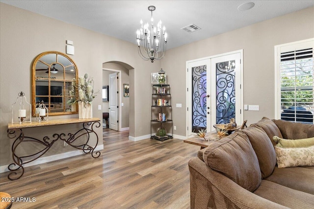 living room featuring arched walkways, wood finished floors, visible vents, baseboards, and french doors