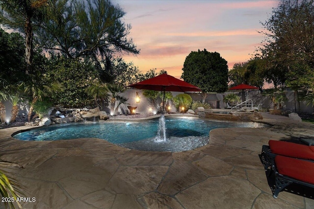 pool at dusk with a patio area, a fenced backyard, and a fenced in pool