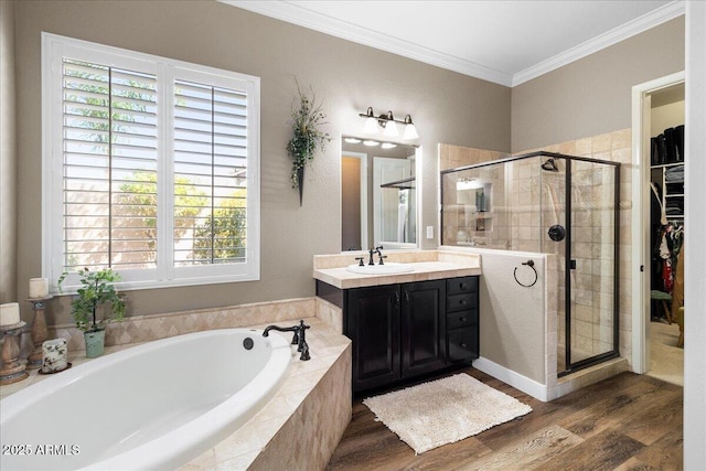 full bathroom featuring a stall shower, ornamental molding, wood finished floors, vanity, and a bath