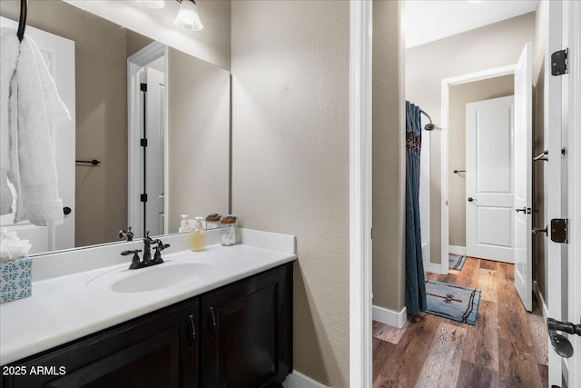 full bathroom with baseboards, wood finished floors, and vanity