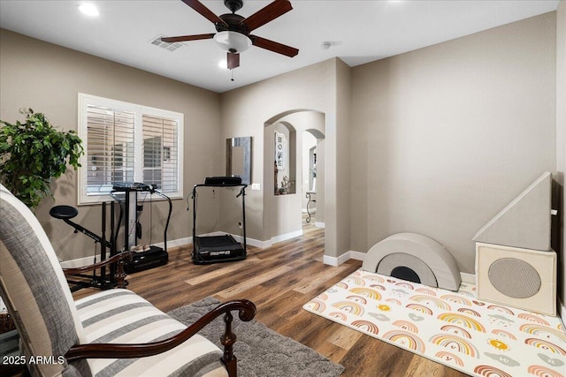 interior space featuring arched walkways, wood finished floors, visible vents, baseboards, and a ceiling fan