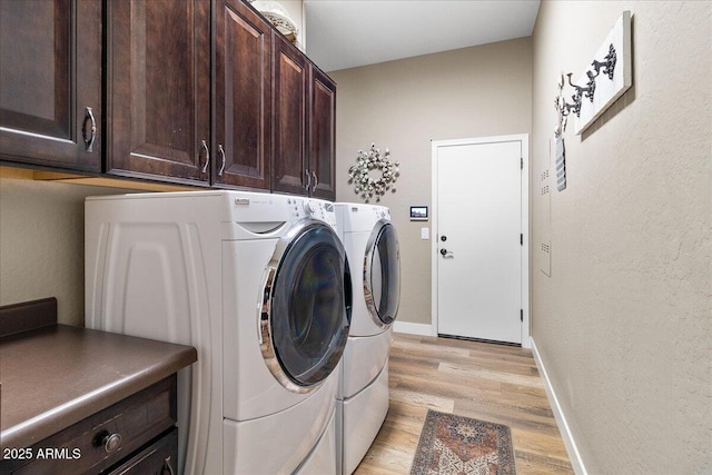 laundry area featuring washer and dryer, baseboards, cabinet space, and light wood finished floors