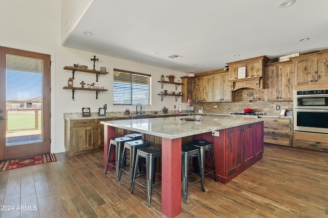 kitchen featuring dark wood-type flooring, light stone counters, a kitchen bar, and a center island