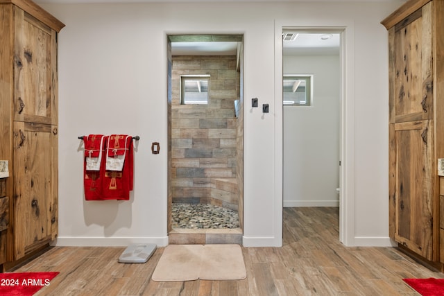 bathroom featuring a wealth of natural light, a shower with shower door, and wood-type flooring