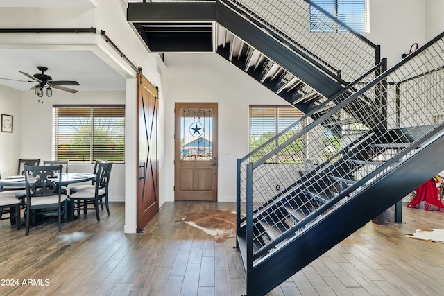 foyer featuring a barn door, hardwood / wood-style floors, ceiling fan, and a healthy amount of sunlight