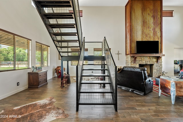 stairway with hardwood / wood-style flooring and a stone fireplace