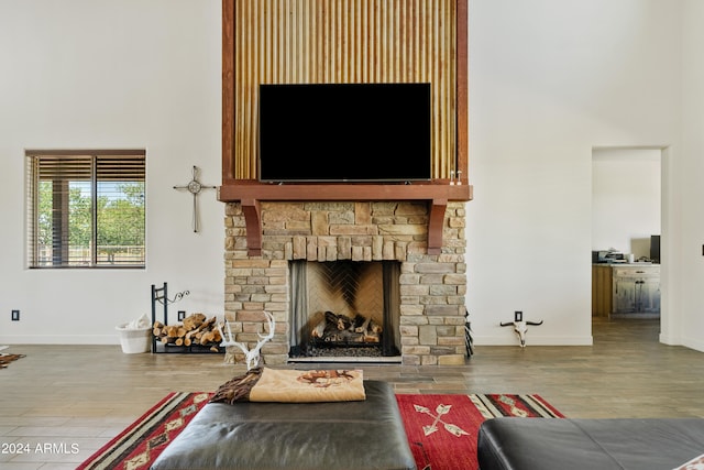 living room with a towering ceiling, hardwood / wood-style flooring, and a stone fireplace