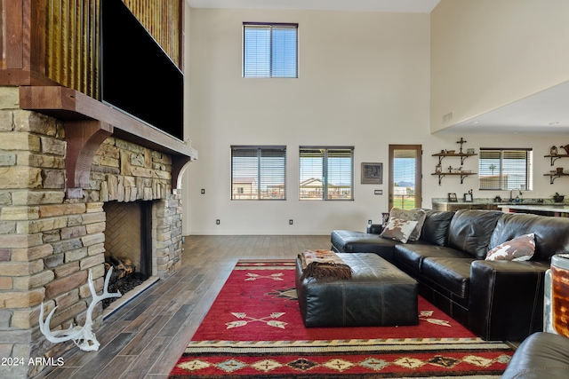 living room with a fireplace, dark wood-type flooring, and a towering ceiling