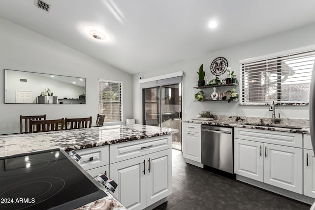 kitchen with dishwasher, stone counters, sink, vaulted ceiling, and white cabinetry