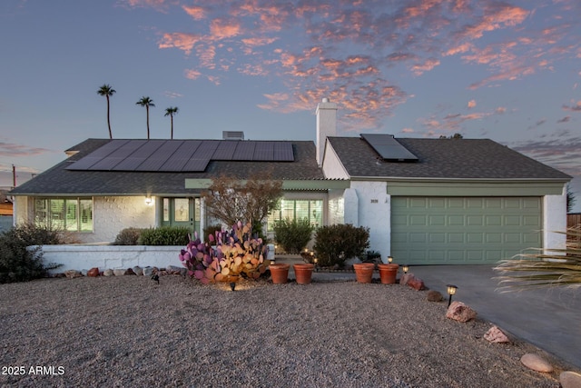 view of front facade with a garage and solar panels