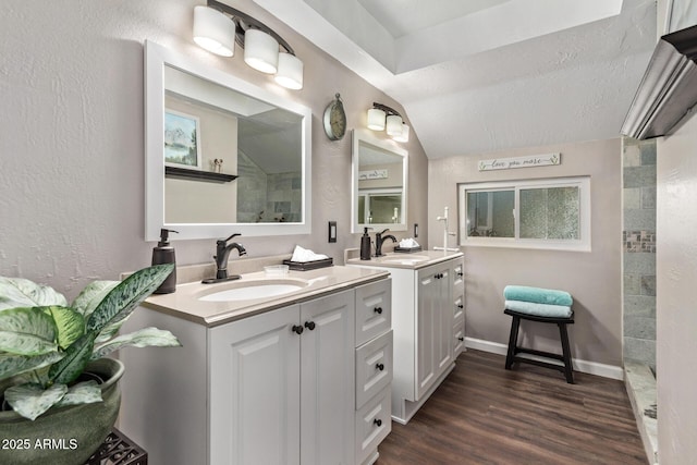 bathroom with a textured ceiling, lofted ceiling, vanity, and wood-type flooring