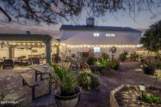 back house at dusk featuring a patio area, an outdoor living space, and a pergola