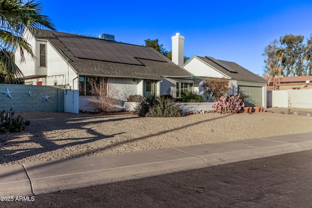 view of front facade featuring solar panels and a garage