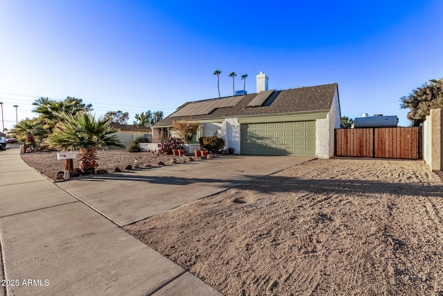 single story home featuring solar panels and a garage