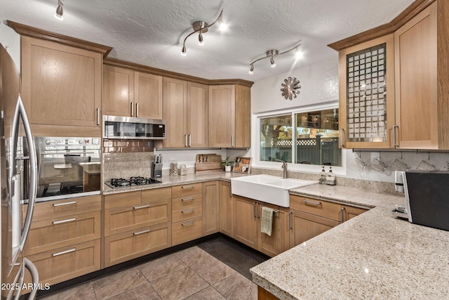 kitchen with sink, appliances with stainless steel finishes, light stone countertops, and a textured ceiling