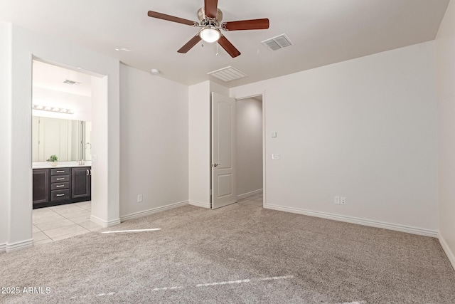 unfurnished bedroom with ceiling fan, light colored carpet, and ensuite bath